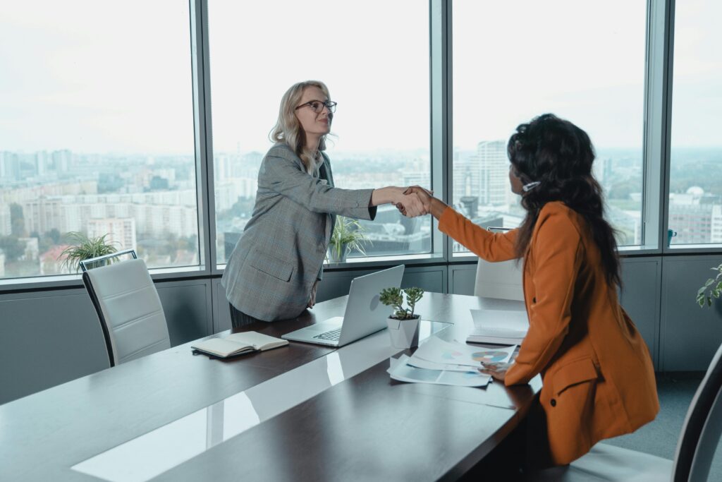 Two professional women shaking hands, highlighting direct sales success.